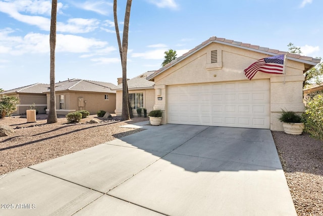 view of front of house featuring a garage, a tiled roof, concrete driveway, and stucco siding