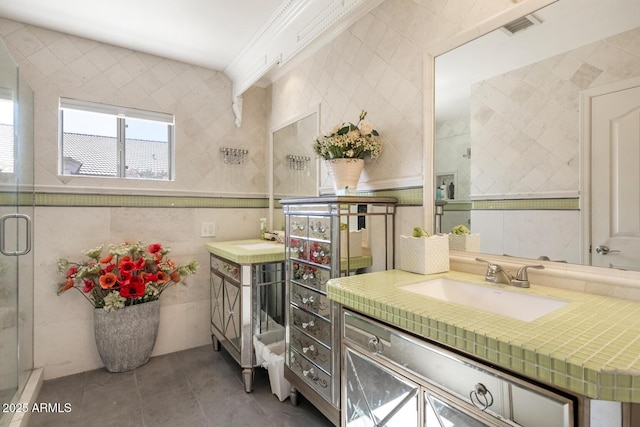 bathroom featuring tile patterned flooring, visible vents, vanity, tile walls, and a stall shower