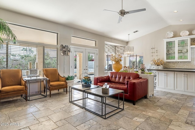 living area with french doors, visible vents, vaulted ceiling, and stone tile floors