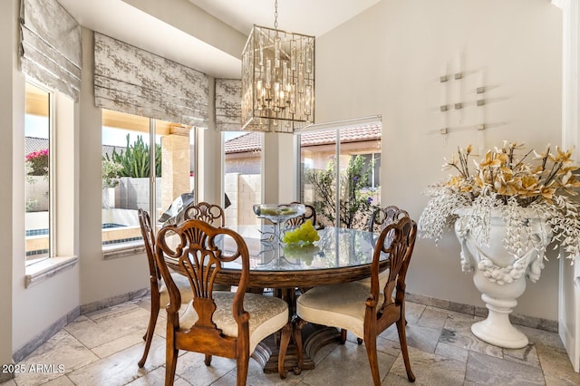 dining space with baseboards, an inviting chandelier, and stone tile floors