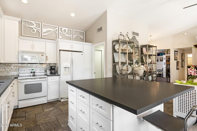 kitchen featuring tasteful backsplash, dark countertops, white appliances, and visible vents