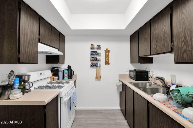 kitchen with gas range gas stove, a sink, dark brown cabinetry, black microwave, and under cabinet range hood