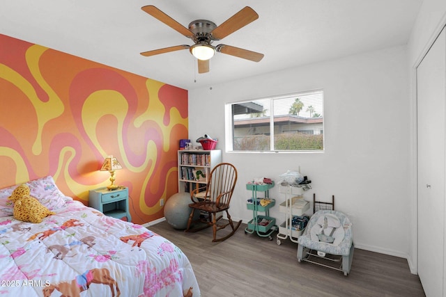 bedroom with a closet, ceiling fan, baseboards, and wood finished floors