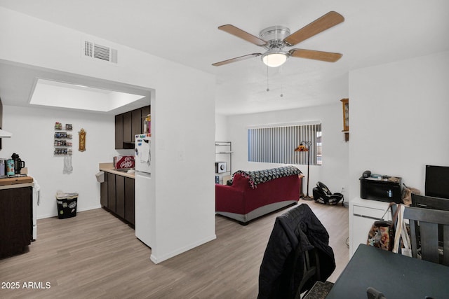 bedroom with visible vents, freestanding refrigerator, ceiling fan, light wood-type flooring, and baseboards