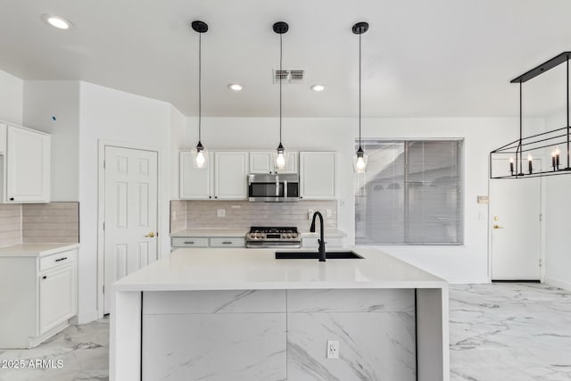 kitchen featuring white cabinetry, appliances with stainless steel finishes, sink, and hanging light fixtures