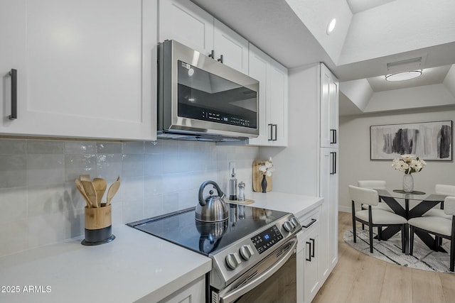 kitchen with white cabinets, appliances with stainless steel finishes, and lofted ceiling