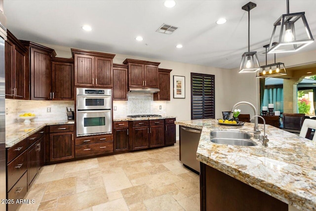 kitchen with visible vents, backsplash, appliances with stainless steel finishes, a sink, and under cabinet range hood