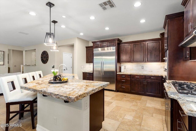 kitchen with sink, hanging light fixtures, a center island with sink, a kitchen breakfast bar, and stainless steel appliances