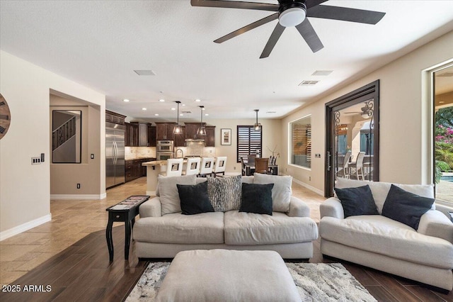 living room featuring a ceiling fan, wood finished floors, visible vents, and baseboards