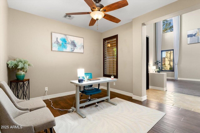 home office featuring a ceiling fan, visible vents, baseboards, and wood finished floors