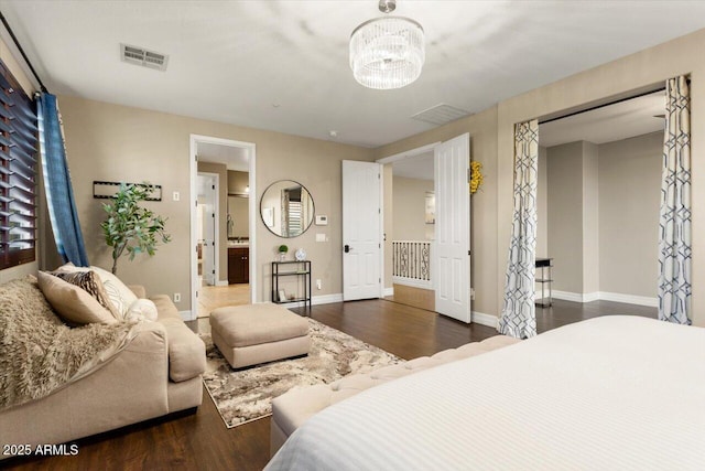 bedroom featuring an inviting chandelier, ensuite bath, and dark hardwood / wood-style flooring