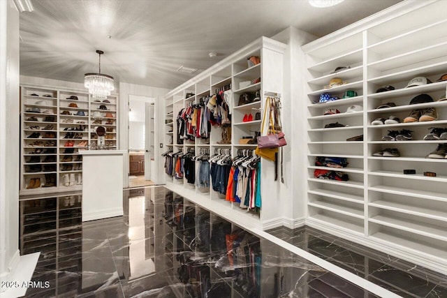 spacious closet featuring marble finish floor and a chandelier