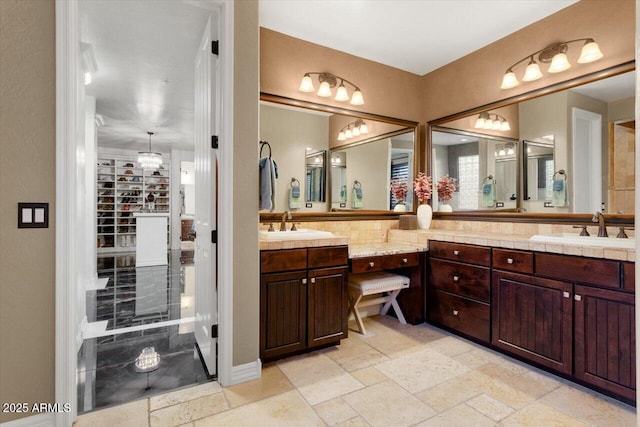 full bath with a sink, stone tile floors, and double vanity