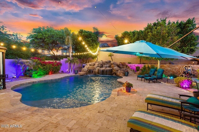 pool at dusk with a patio area and pool water feature