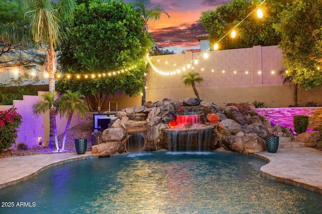 pool at dusk featuring pool water feature