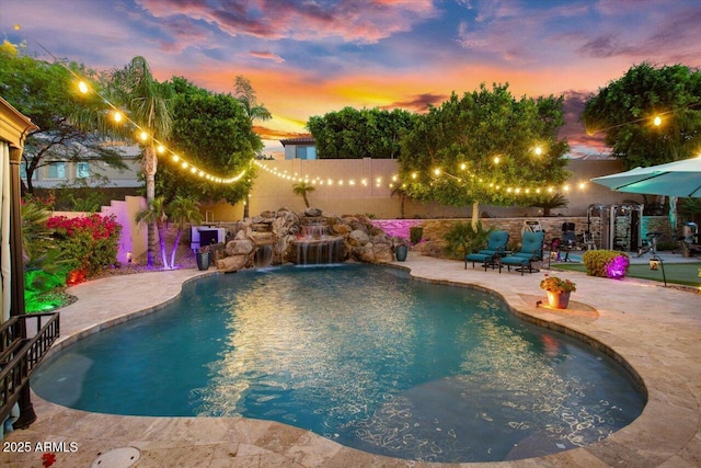 pool at dusk featuring a patio and pool water feature