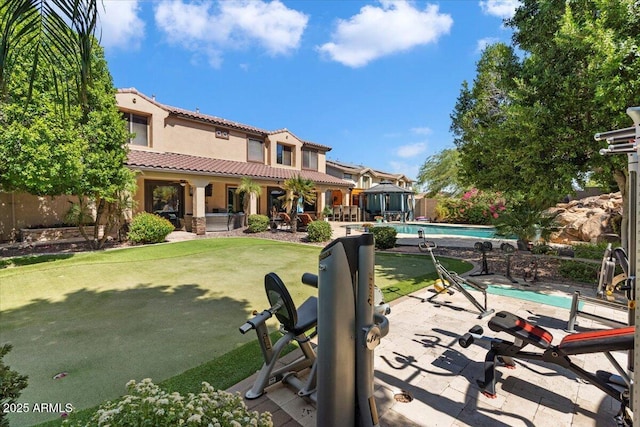 back of house featuring a yard, an outbuilding, a fenced in pool, and a patio