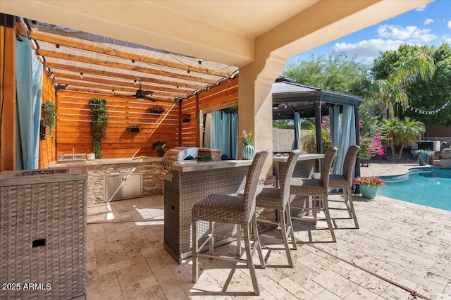 view of patio with area for grilling, outdoor dining space, ceiling fan, exterior kitchen, and an outdoor pool