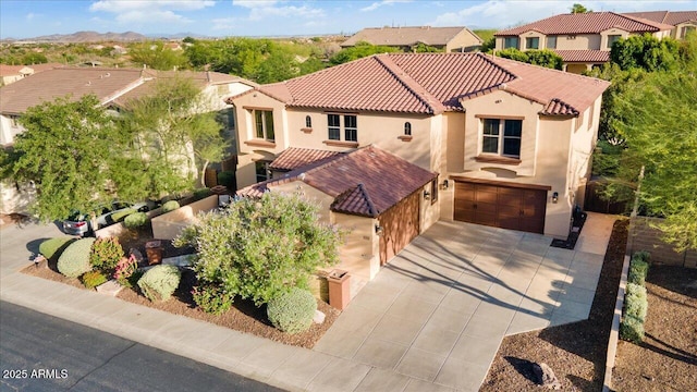 mediterranean / spanish-style home with a garage, driveway, a tile roof, and stucco siding