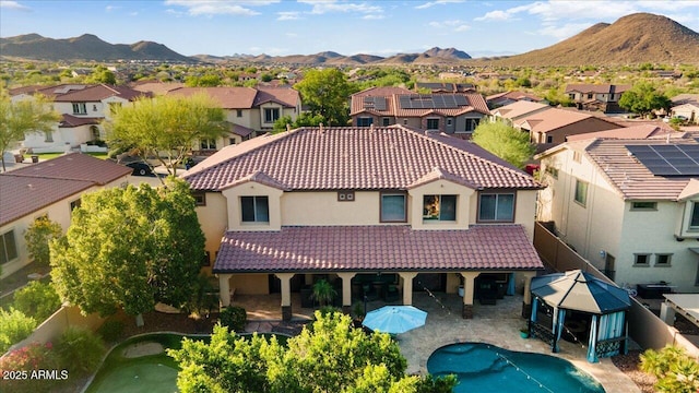 rear view of property with a residential view, a tile roof, and a mountain view