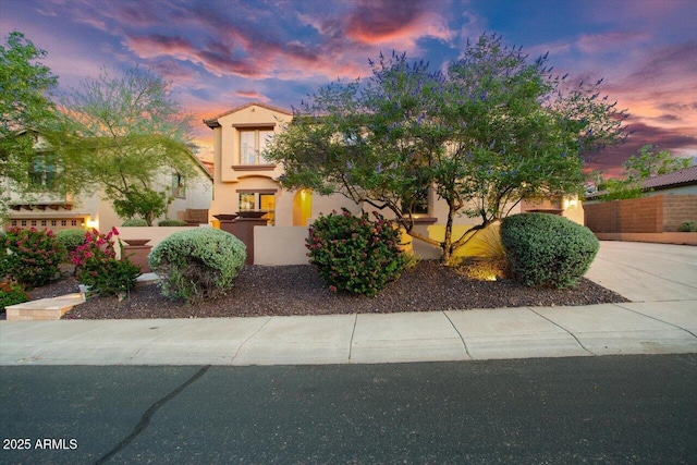 view of front of home with concrete driveway, fence, and stucco siding