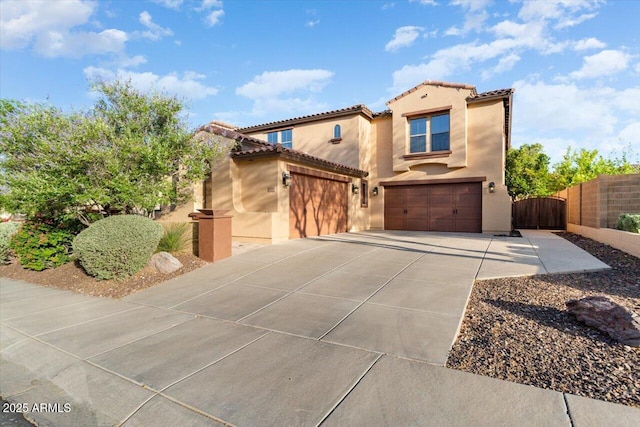 mediterranean / spanish home featuring an attached garage, a tile roof, driveway, a gate, and stucco siding