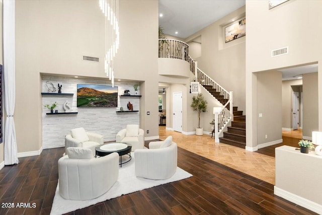 living room featuring wood tiled floor, stairs, visible vents, and baseboards