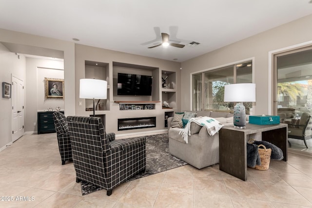 living room featuring a ceiling fan, a glass covered fireplace, light tile patterned floors, and visible vents