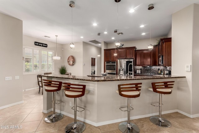 kitchen featuring light tile patterned floors, dark stone counters, a kitchen breakfast bar, and tasteful backsplash