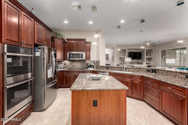 kitchen with visible vents, a center island, a sink, stainless steel appliances, and light tile patterned flooring