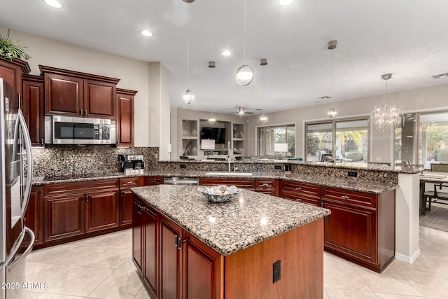 kitchen featuring dark brown cabinets, appliances with stainless steel finishes, a sink, decorative backsplash, and a kitchen island