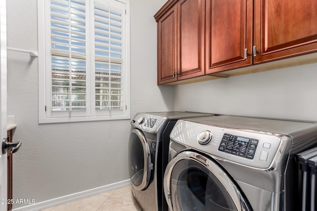 laundry area featuring light tile patterned floors, baseboards, cabinet space, and washer and dryer