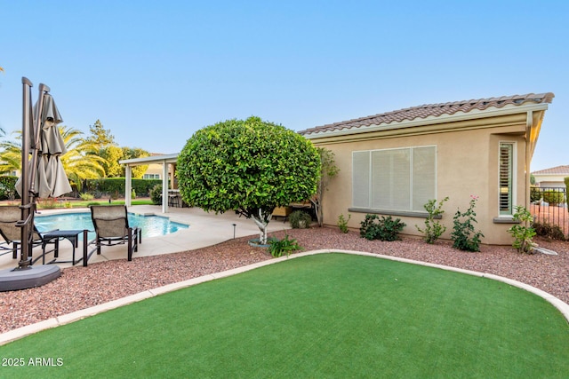 exterior space with a tiled roof, a patio area, a fenced in pool, a fenced backyard, and stucco siding