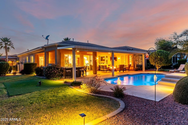 exterior space featuring outdoor dry bar, a patio, a yard, and an outdoor pool