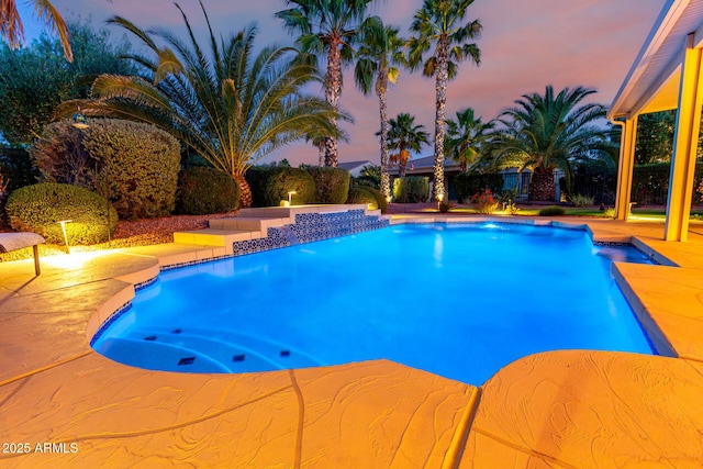 pool at dusk featuring a patio and an outdoor pool