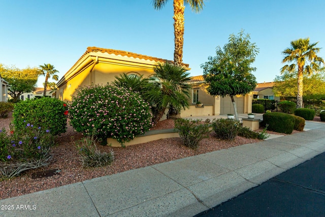mediterranean / spanish-style house with a garage, stucco siding, and a tiled roof