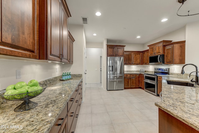 kitchen with light stone countertops, appliances with stainless steel finishes, and sink