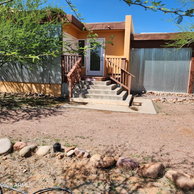 doorway to property with stucco siding and fence