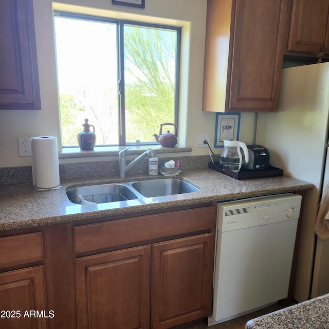kitchen featuring dishwasher, a sink, and brown cabinets