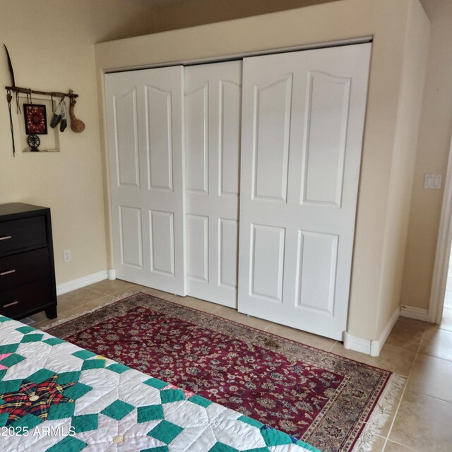 unfurnished bedroom with tile patterned flooring, a closet, and baseboards