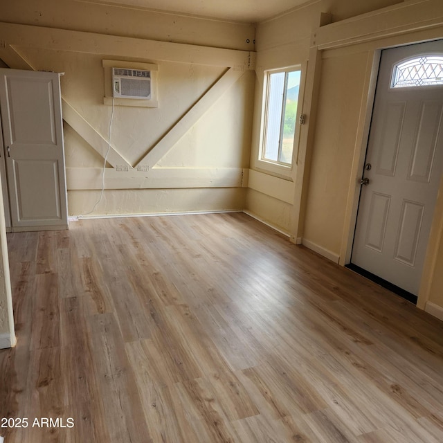 entrance foyer featuring a wall mounted air conditioner, light wood-style floors, and baseboards