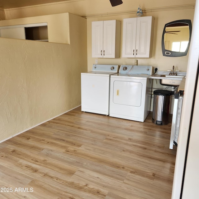 laundry area with separate washer and dryer, cabinet space, a textured wall, light wood-style flooring, and a ceiling fan