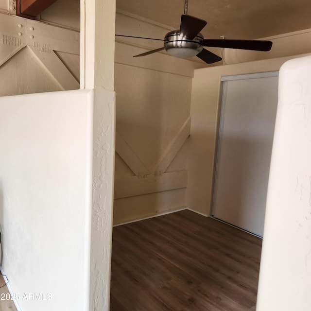 empty room with wood finished floors, a ceiling fan, and attic access