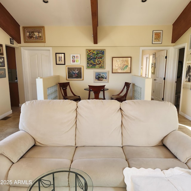 living area featuring baseboards and beamed ceiling