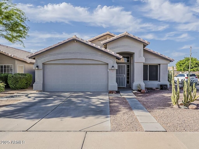 ranch-style house featuring driveway, stucco siding, an attached garage, and a tile roof