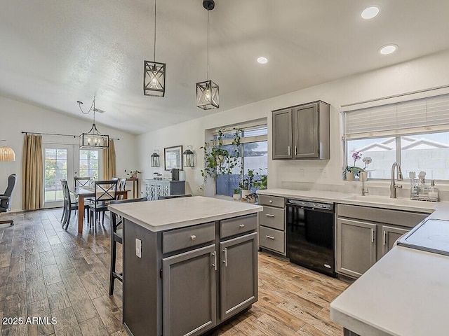 kitchen featuring black dishwasher, light countertops, a sink, and vaulted ceiling