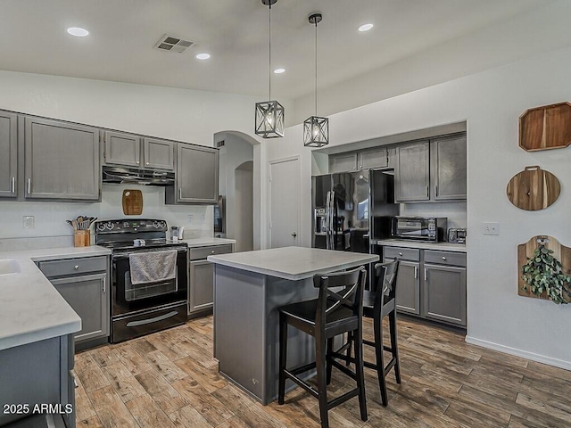 kitchen featuring gray cabinets, visible vents, black appliances, arched walkways, and under cabinet range hood