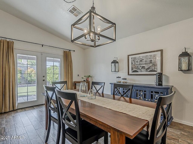 dining space featuring lofted ceiling, a notable chandelier, visible vents, and wood finished floors