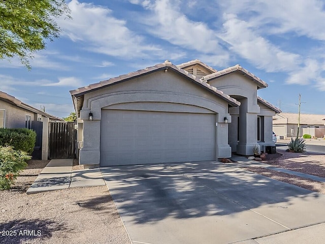 view of front facade with stucco siding, a garage, a tiled roof, and driveway