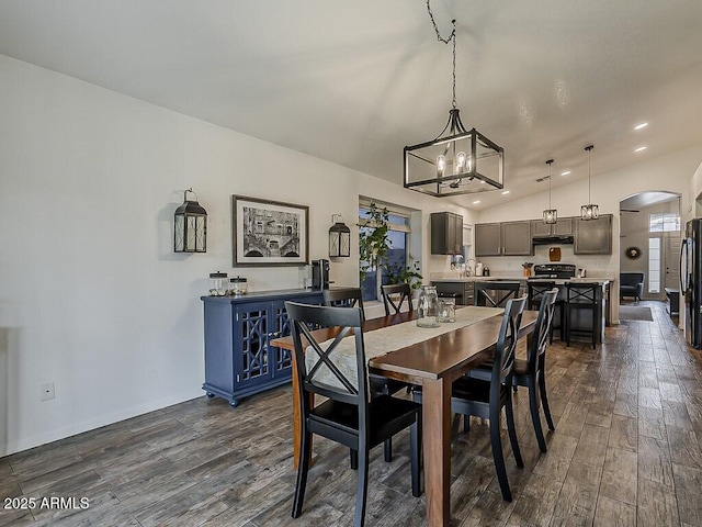 dining area featuring arched walkways, recessed lighting, and dark wood-style floors